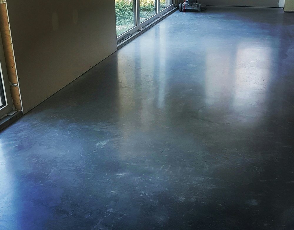 High-gloss shiny burnished concrete floor showcasing natural steel-trowel movements and a mirror finish in a Wollongong home.