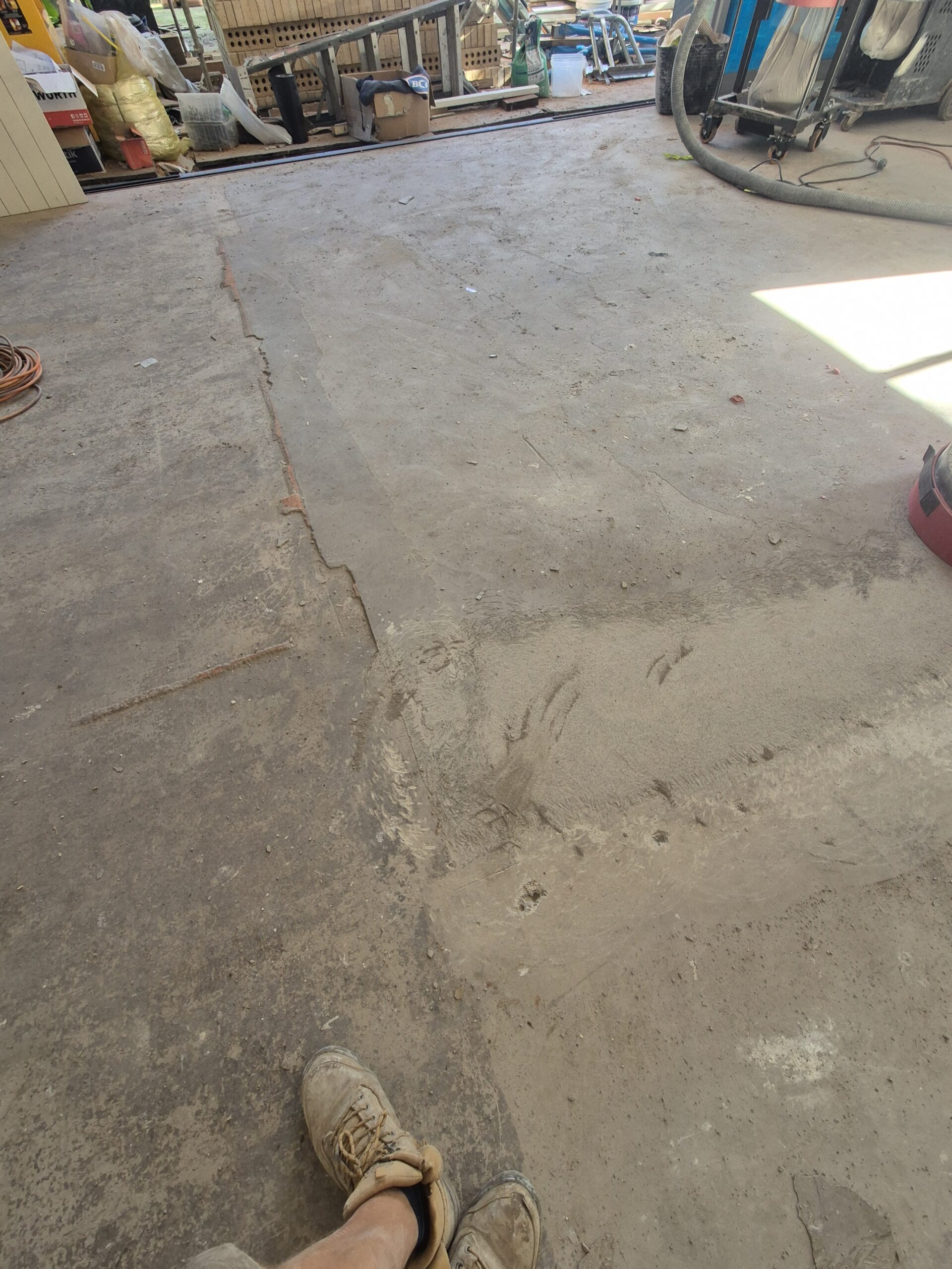 A close-up, angled shot of an old concrete slab in Ulladulla after restoration. The surface shows a clean, smooth, matte finish achieved by grinding off a layer of Ardit levelling compound