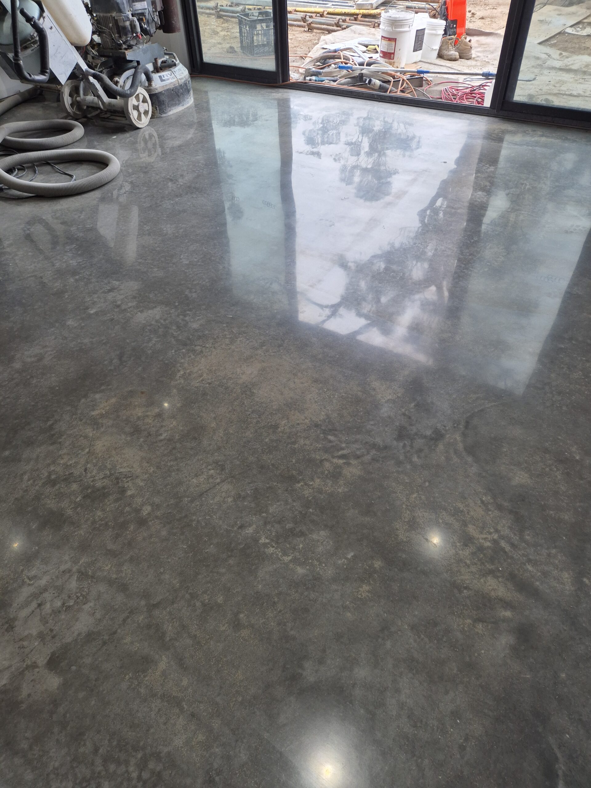 High-gloss shiny burnished concrete floor showcasing natural steel-trowel movements and a mirror finish in a Wollongong home.