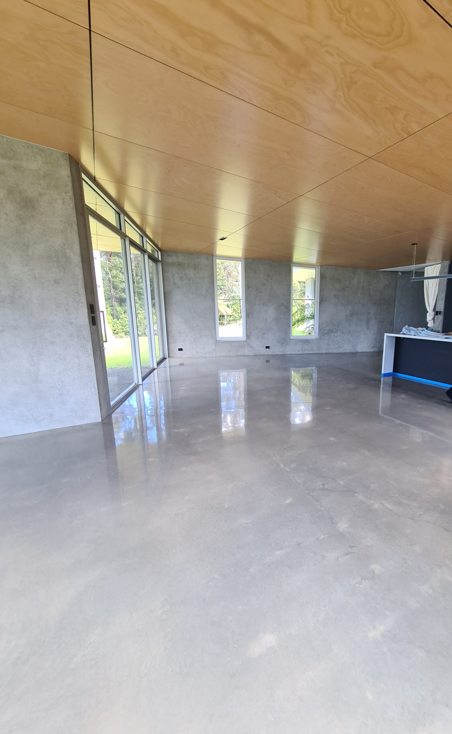 High-gloss shiny burnished concrete floor showcasing natural steel-trowel movements and a mirror finish in a Wollongong home.