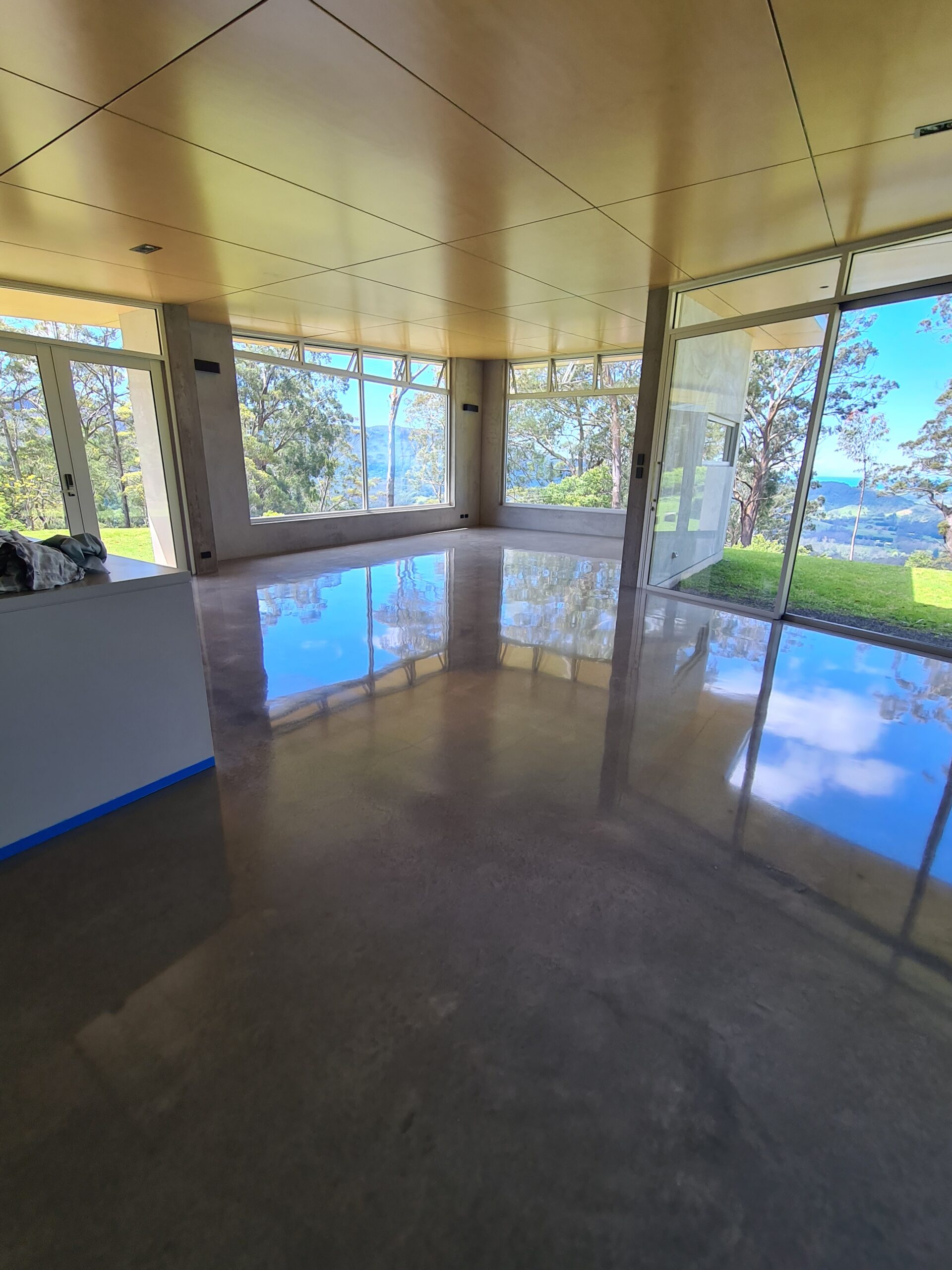 High-gloss shiny burnished concrete floor showcasing natural steel-trowel movements and a mirror finish in a Wollongong home.